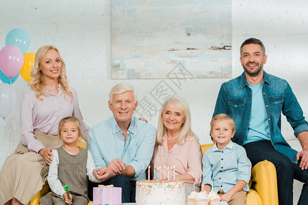 幸福的家庭坐在生日蛋糕旁边看背景图片