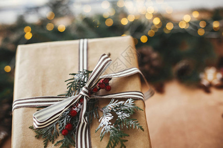 圣诞节快乐乡村木桌上时尚质朴的圣诞礼物和灯松枝锥体姜饼线肉桂茴图片