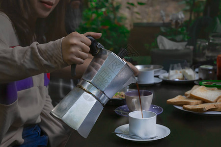 女青年在早餐桌上把咖啡倒进咖啡图片
