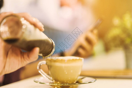 一个女人把糖浆倒进咖啡杯的碟子里图片
