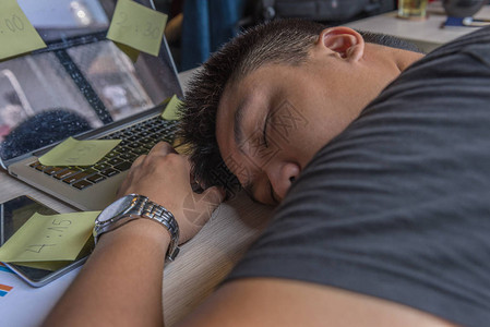 疲倦的办公室男职员在桌子上睡着时满都图片