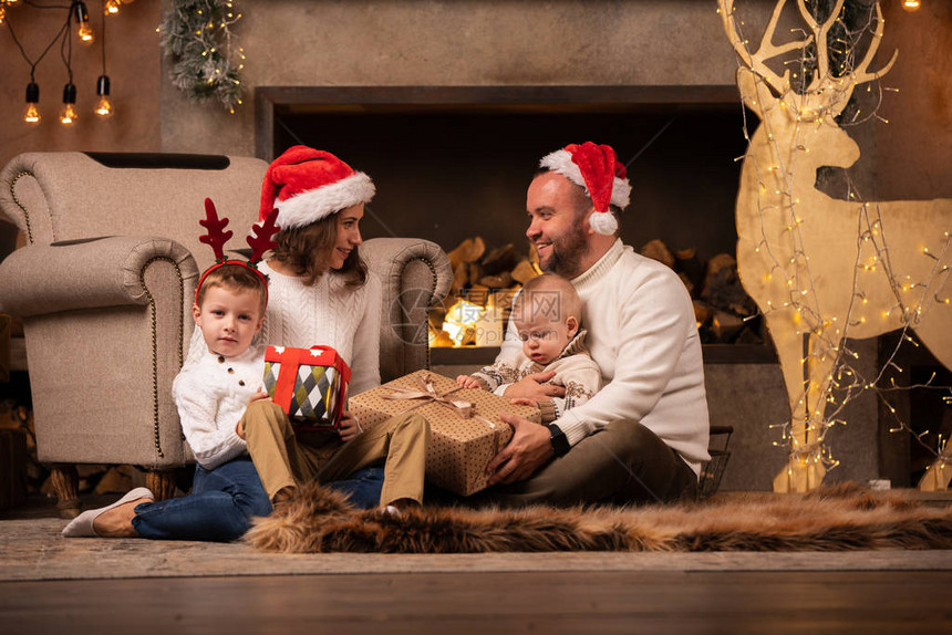 父母在壁炉与儿子的幸福鹿与羊圈在圣诞节图片