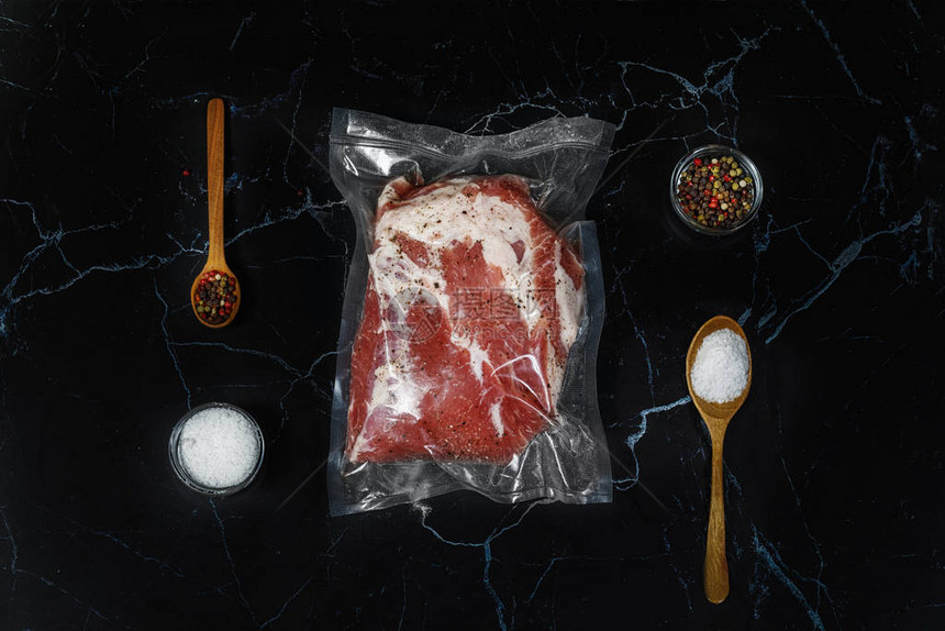 盐和肉是黑色背景上的真空包装香料图片