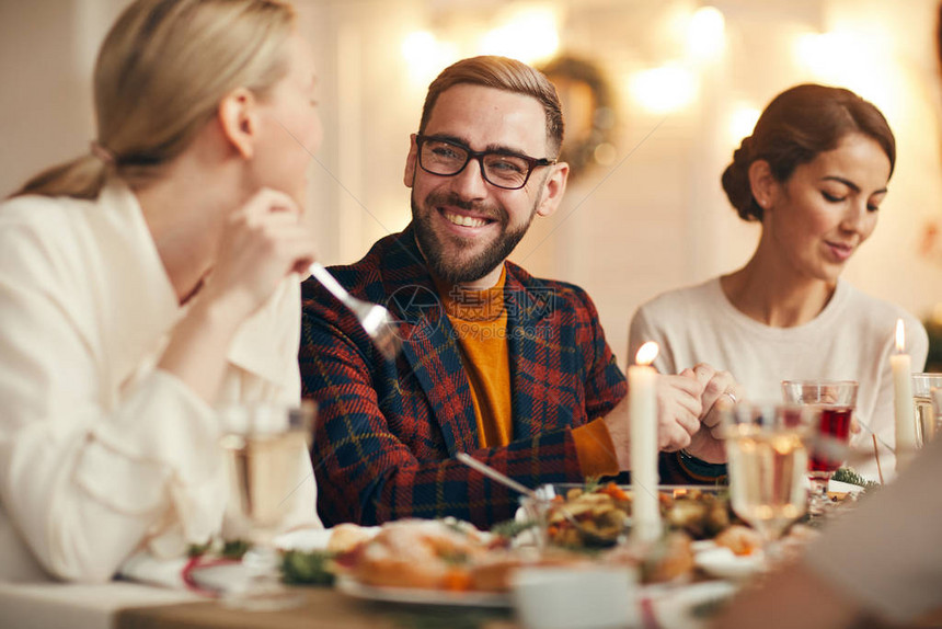 英俊成年男子在庆祝圣诞节时与朋友和家人一起共进晚餐桌前欢图片