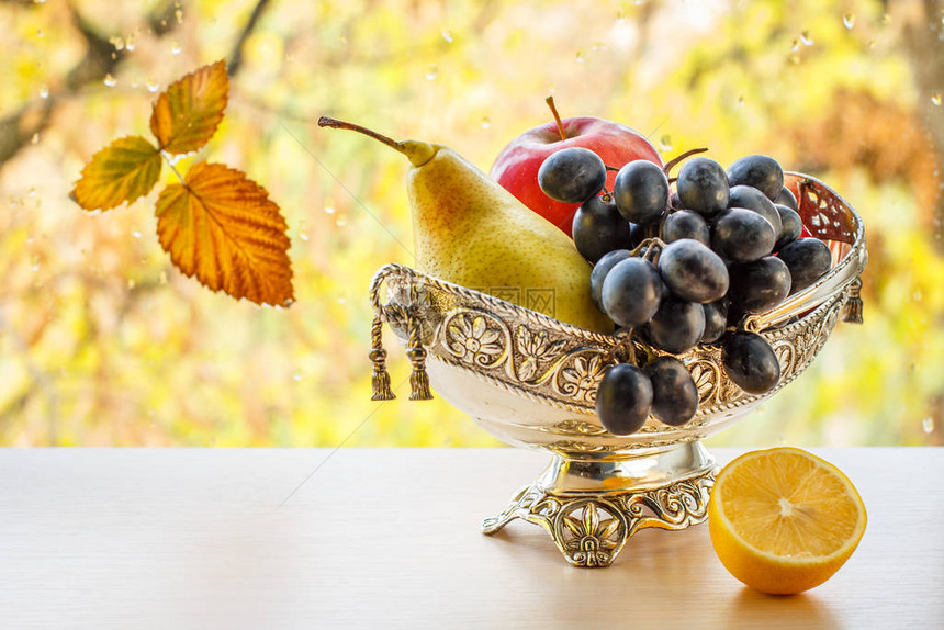 有黄色梨子葡萄和柠檬的金属花瓶图片
