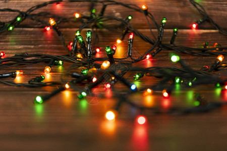棕色木制背景上的彩色圣诞花环灯带有Copyspace的圣诞灯图片