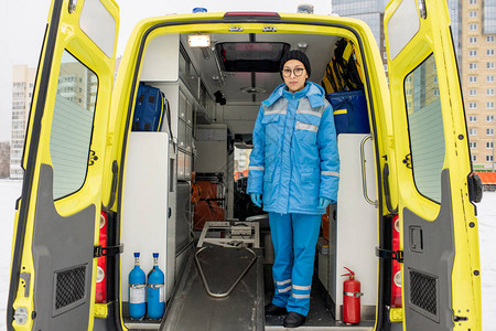 身着制服的年轻女护理人员在救护车内用空担架站图片