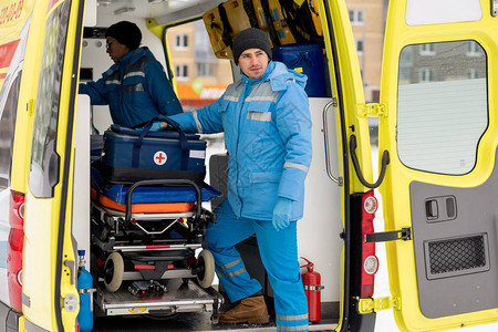 配备急救包的年轻男护理员在救护车门上用担架站图片