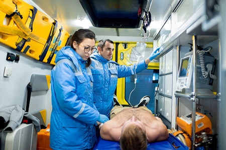 两名护理人员之一检查在担架上无意识的病人图片