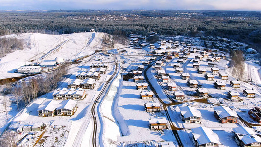 在阳光明媚的冬日飞越被雪覆盖的城市住宅区冬季美丽房屋的空中景观图片
