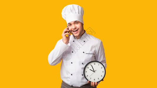 餐饮主厨在黄工作室背景旁谈论手机控时钟图片