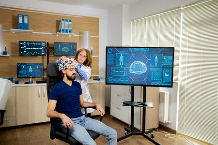 医生在一名男病人的头上安装扫描装置图片