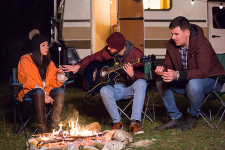 露营者玩吉他和烤棉花糖在山地野营区收图片