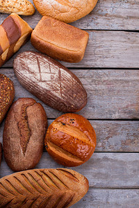 工匠面包和烘焙产品质朴的木制背景上美味的黑面包和小圆面包的顶部视图图片