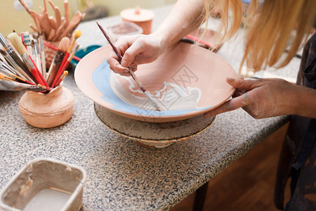 波特女人画一个陶瓷盘子女孩用刷子在陶器上画创建粘图片