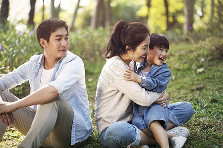 亚洲家庭母亲父子坐在草地上放松在图片