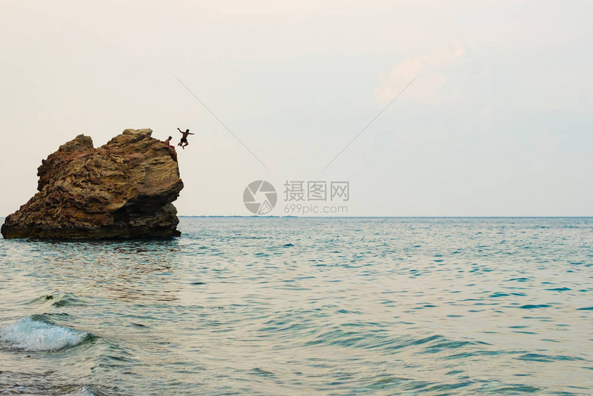 岩石海岸上有巨石一块石头跳入海人中休息在海图片