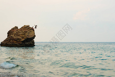 岩石海岸上有巨石一块石头跳入海人中休息在海图片