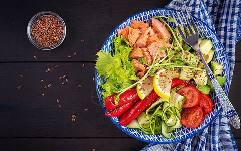 健康烤三文鱼鳄梨番茄黄瓜辣椒粉和奇亚籽蓝色碗中的均衡午餐碗图片