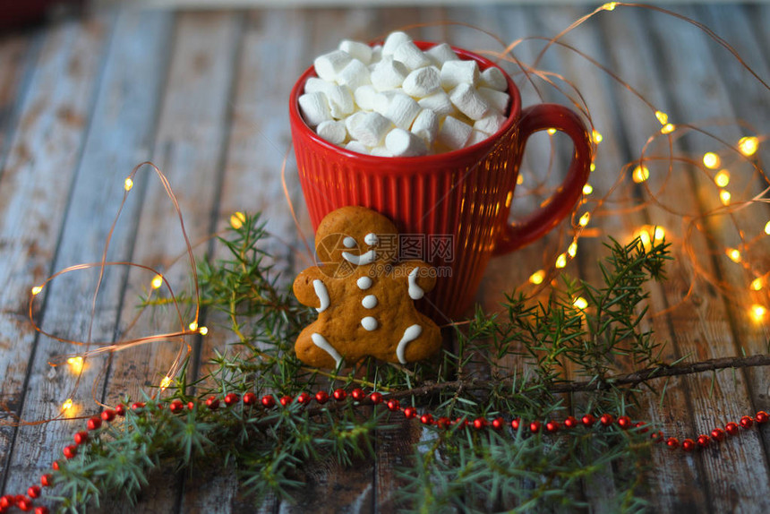 可或热巧克力配棉花糖在质朴的桌子上圣诞节或作文拿着棒糖的姜饼人用烟火在红色杯子里近距离观察棉花糖图片
