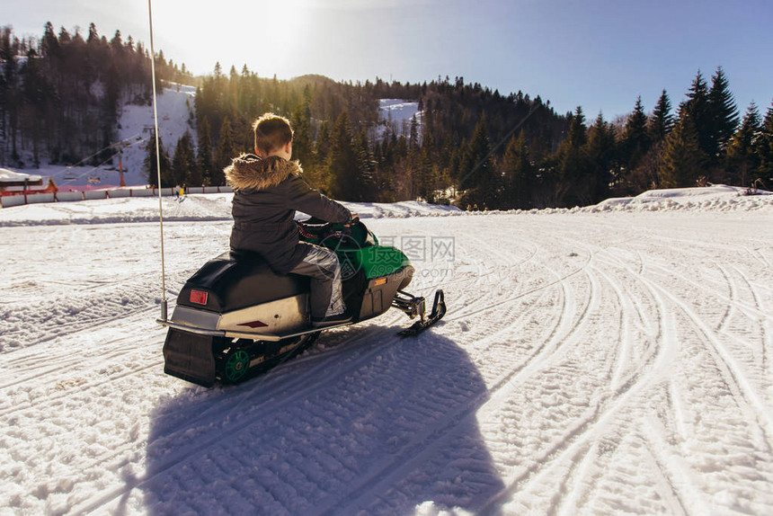 男孩在冬季风景中驾驶雪地摩托图片