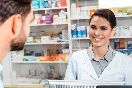 药剂师在药店柜台向顾客微笑图片