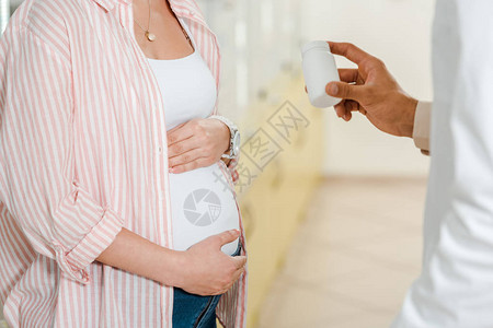 药剂师向孕妇提供罐子和药丸图片