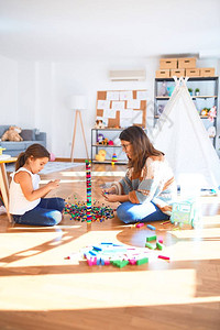 漂亮的老师和幼儿在幼儿园的许多玩具周图片