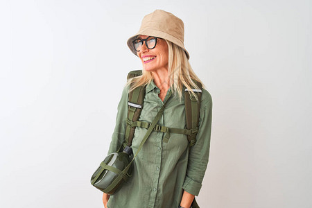 中年远足妇女带着背负式帽子食堂眼镜与孤立的白色背景相隔绝地站在一边图片