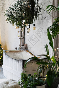 冬季风格室内房间的白色舒适浴室的垂直照片装饰过的新年树花环灯和家图片