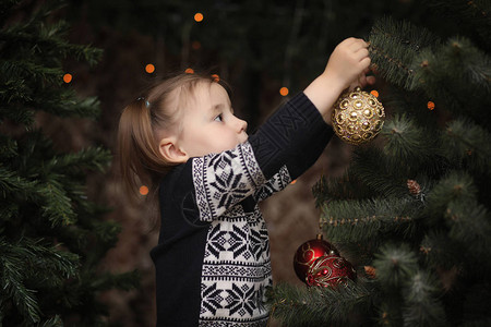 新年树旁的一个小孩子们装饰圣诞树工作室里一棵绿树旁穿背景图片