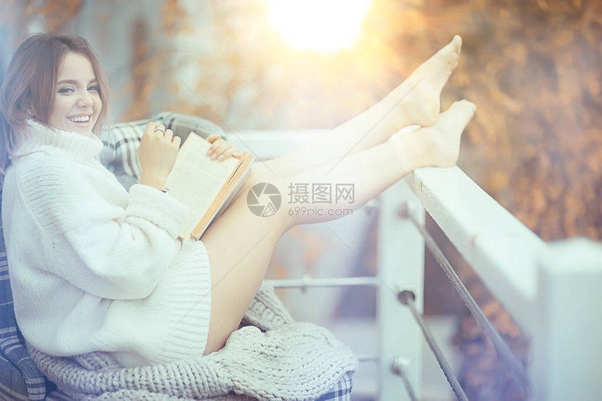 穿着毛衣的女孩在公园里读一本关于阳台的书季图片