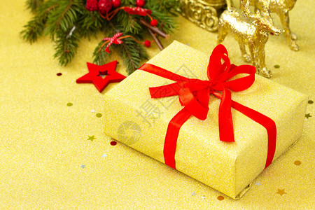 圣诞礼物盒是金盒配有红丝带和树枝装饰图片