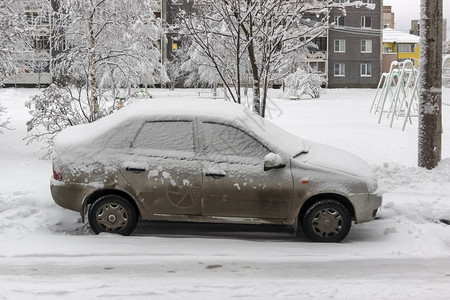 冬天停在城市院子里的廉价汽车被冰雪覆盖图片