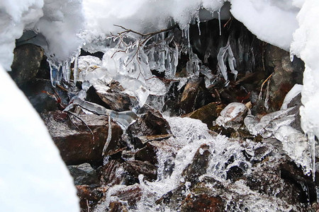 山涧流过石头雪和冰柱图片