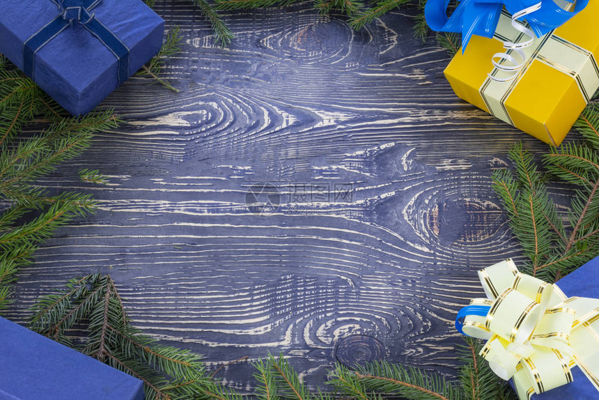 空间文本木质深色背景上它的木材纹理围绕圣诞树腿有丝带和弓的礼物盒图片