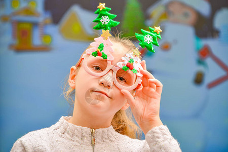 一个戴着新年假期眼镜的快乐而快乐的女孩在等待惊喜礼物图片