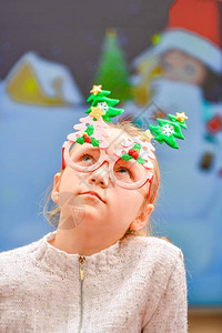 一个戴着新年假期眼镜的快乐而快乐的女孩在等待惊喜礼物图片