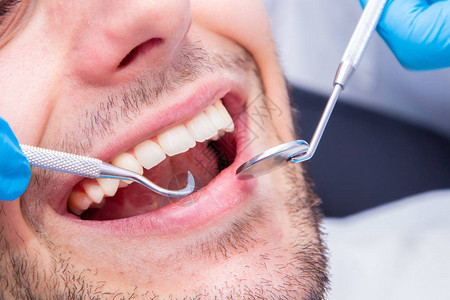 患者口腔中牙医工具的特写高清图片