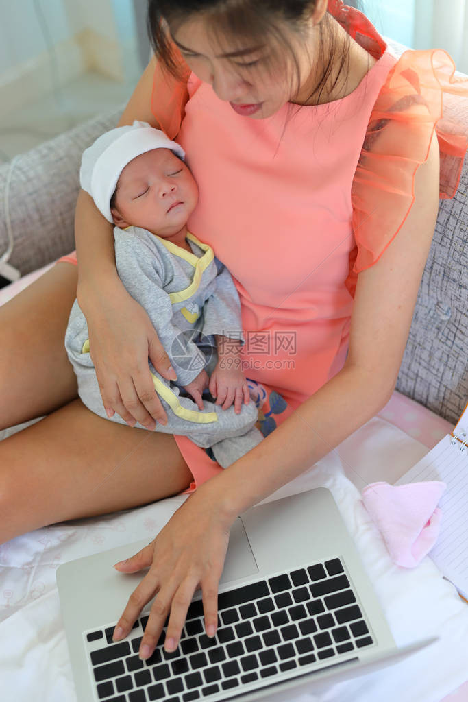 使用笔记本电脑的女商人和她的孩子睡在家庭商务办公室图片
