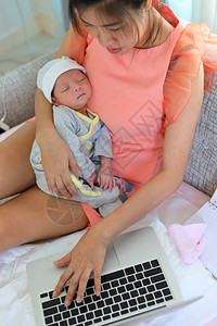 使用笔记本电脑的女商人和她的孩子睡在家庭商务办公室图片
