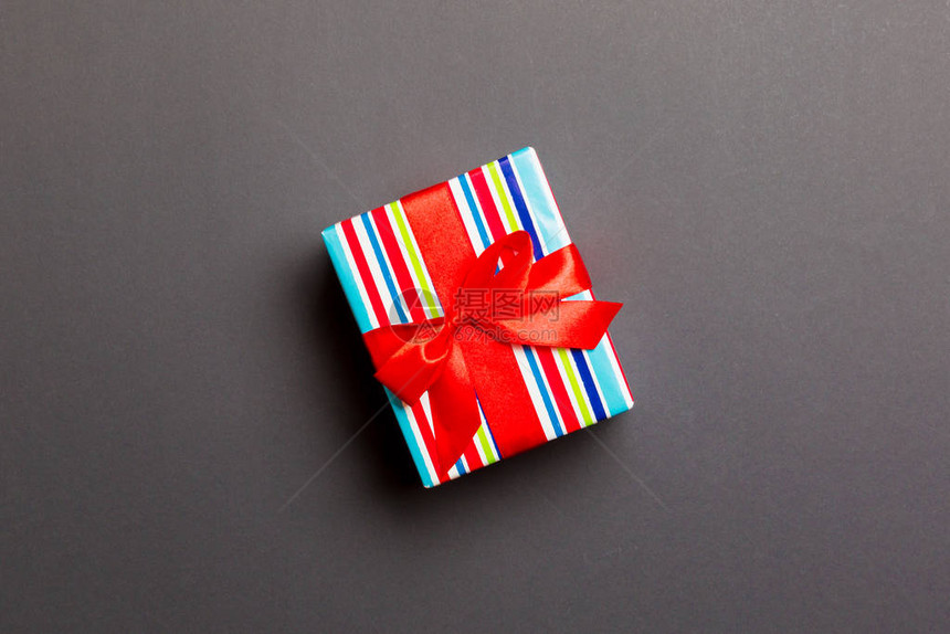 用黑色背景上的红丝带用纸包裹圣诞节或其他节日手工制作的礼物图片