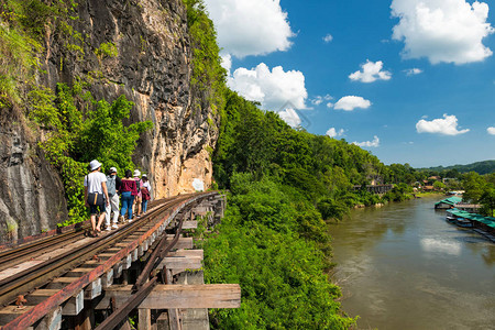 一群亚洲旅游朋友走在泰国北碧府桂河附近的二战历史铁路上图片