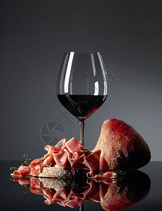 黑反射背景的红葡萄酒和百合香肠都配有西巴塔红葡高清图片