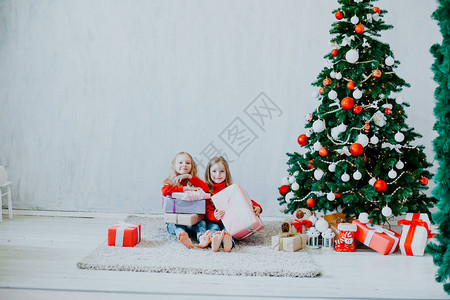 圣诞假期两个带礼物的女孩用灰色背景礼图片