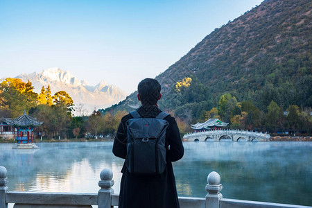 在玉龙雪山背景的黑龙池旅游的青年旅行者图片