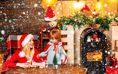 快乐微笑的金发年轻妈和她的小孩在秋天冬装饰假期礼物盒圣诞礼物圣诞快图片