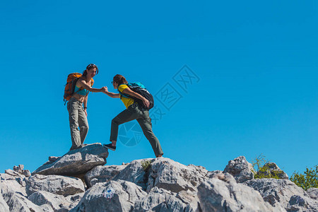 女人帮助朋友爬石头图片