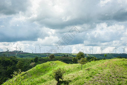 可再生能源风车力涡轮机在山地景观与高压杆图片