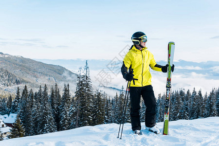 穿着戴滑雪棍头盔的欢快滑雪手站在雪图片